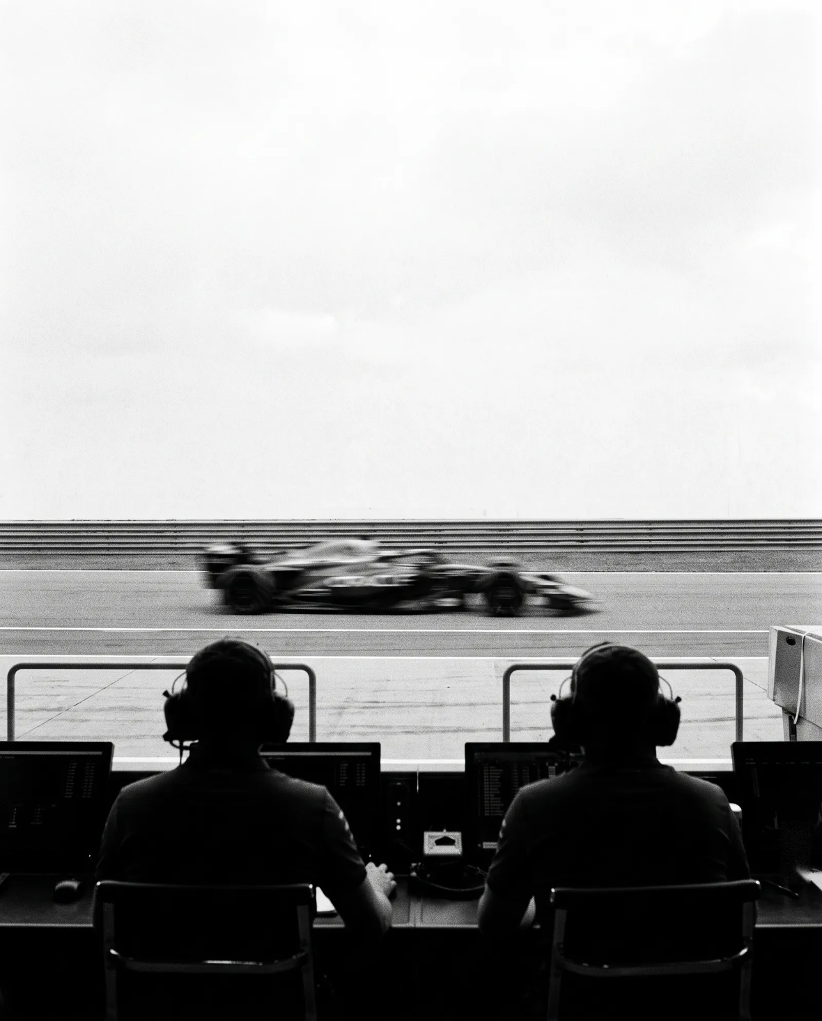 Two engineers on the pit wall watching a car pass